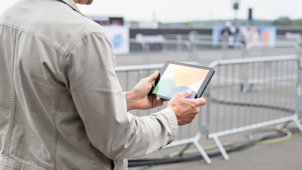 Organisateur vérifiant un plan sur tablette devant des barrières de sécurité événementielles